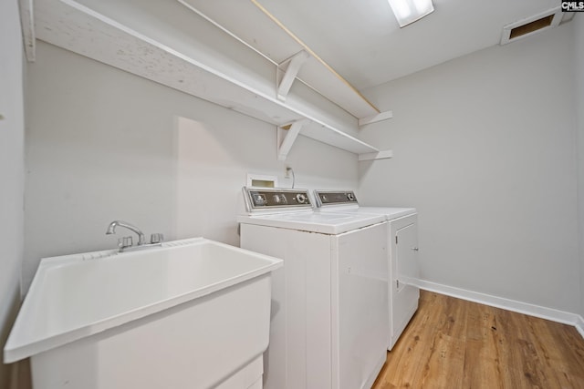 washroom featuring laundry area, visible vents, light wood-style floors, washing machine and dryer, and a sink