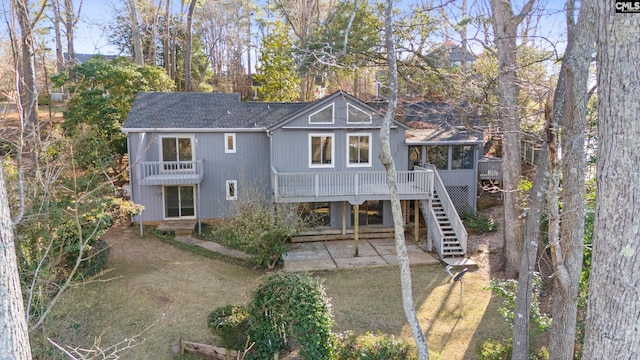 view of front of home featuring roof with shingles, stairway, a patio area, and a sunroom