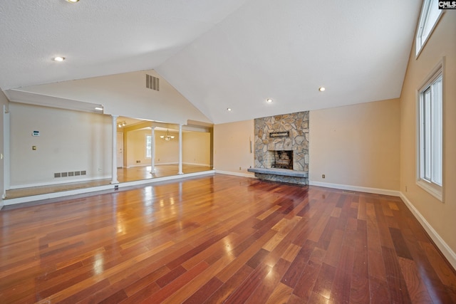 unfurnished living room featuring a stone fireplace, wood-type flooring, visible vents, and baseboards