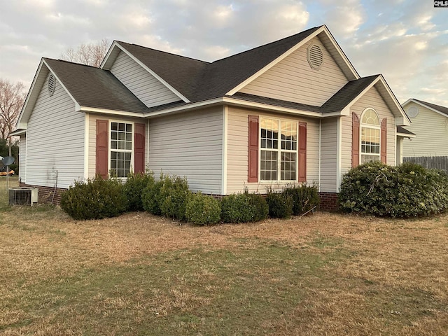 view of side of property featuring roof with shingles and a yard