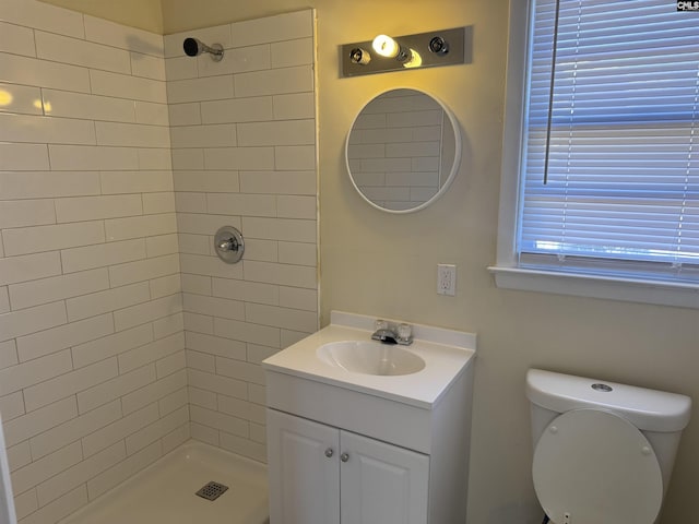 full bath with a tile shower, vanity, and toilet