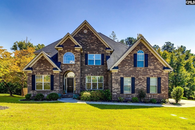 craftsman-style house with brick siding, a shingled roof, and a front yard