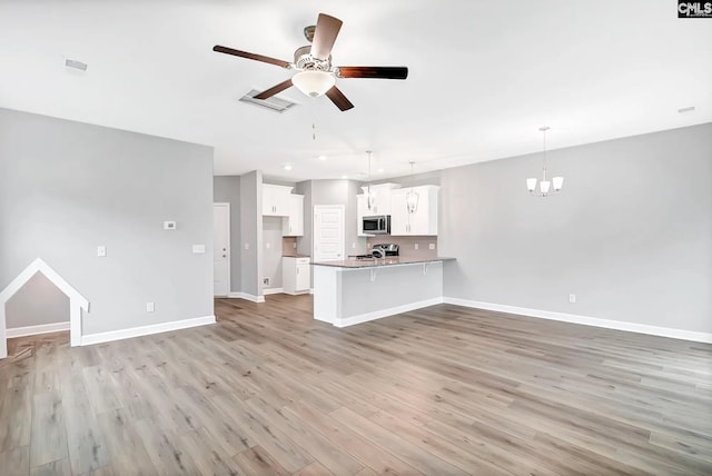 unfurnished living room featuring light wood-style flooring, recessed lighting, ceiling fan with notable chandelier, visible vents, and baseboards