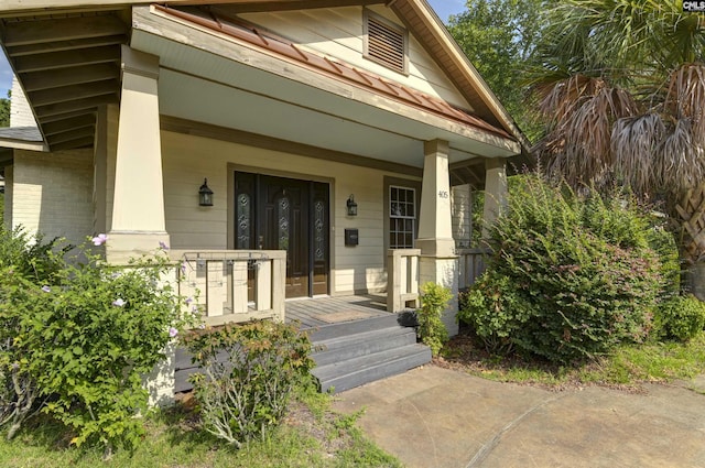 property entrance featuring a porch and brick siding