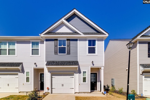 multi unit property featuring a garage, a shingled roof, and concrete driveway