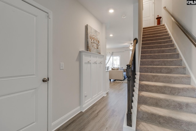 stairs with baseboards, wood finished floors, and recessed lighting