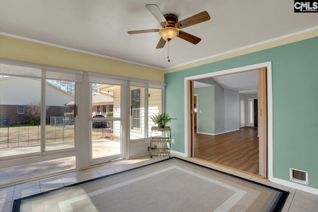 doorway with visible vents, baseboards, ceiling fan, ornamental molding, and tile patterned floors