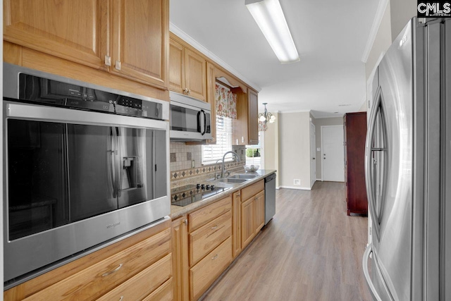 kitchen featuring backsplash, crown molding, light countertops, appliances with stainless steel finishes, and a sink