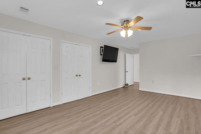 unfurnished bedroom featuring light wood finished floors, baseboards, visible vents, and two closets
