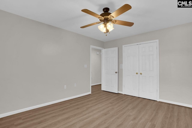 unfurnished bedroom with a closet, baseboards, wood finished floors, and a ceiling fan