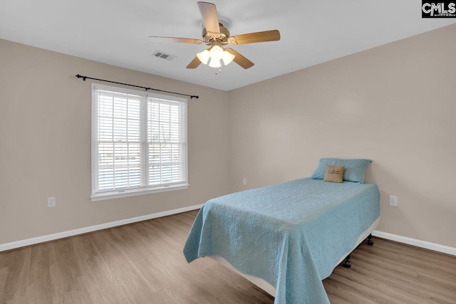 bedroom with visible vents, wood finished floors, baseboards, and ceiling fan