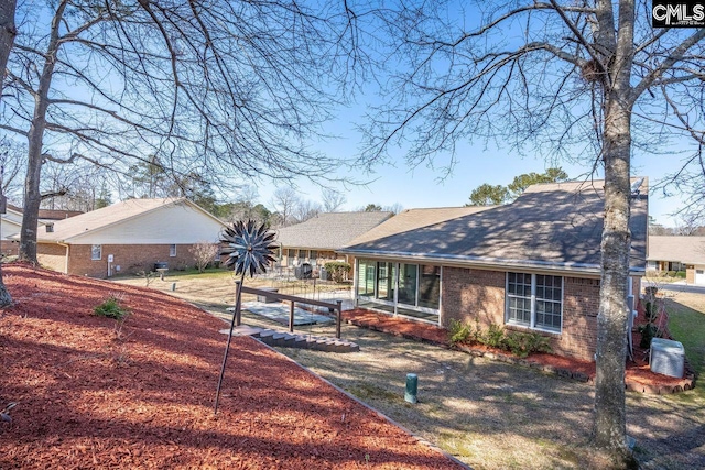 back of house featuring central air condition unit, brick siding, and a shingled roof