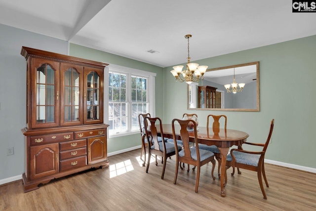 dining space featuring a chandelier, visible vents, light wood-type flooring, and baseboards