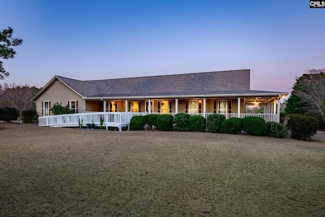 rear view of property with a ceiling fan, covered porch, and a yard