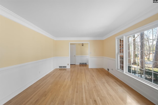 unfurnished room featuring wainscoting, visible vents, crown molding, and light wood finished floors