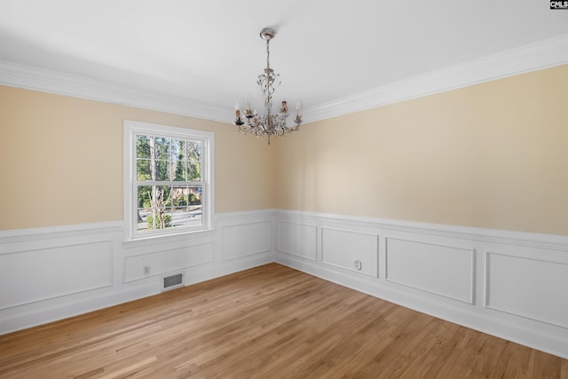 empty room featuring ornamental molding, visible vents, light wood-style flooring, and an inviting chandelier