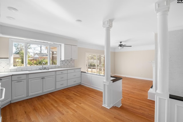 kitchen with a sink, a healthy amount of sunlight, ornamental molding, decorative backsplash, and decorative columns