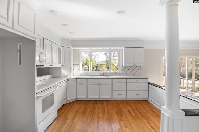 kitchen featuring white appliances, a sink, light countertops, tasteful backsplash, and ornate columns