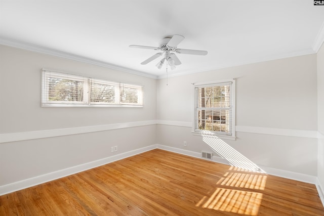 empty room featuring baseboards, visible vents, crown molding, and wood finished floors