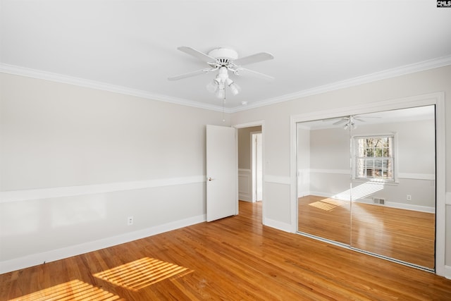 unfurnished bedroom featuring a closet, visible vents, crown molding, and light wood finished floors