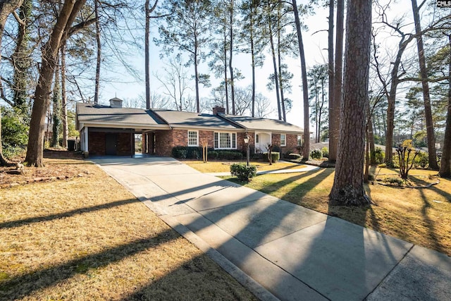 single story home featuring brick siding, driveway, a carport, a front lawn, and a chimney