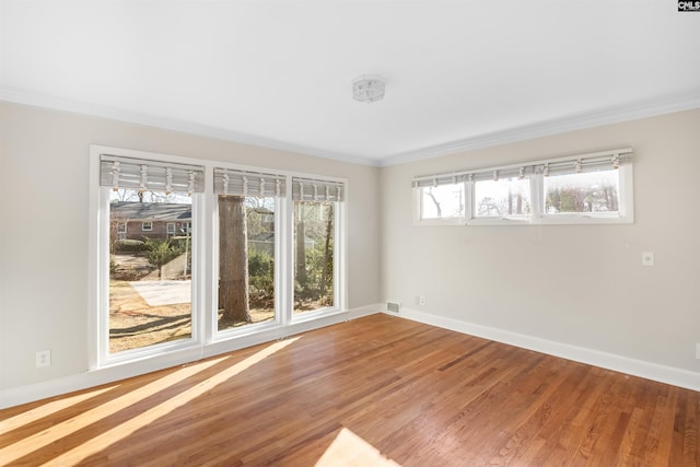 spare room featuring ornamental molding, wood finished floors, visible vents, and baseboards