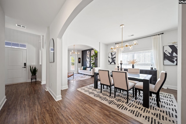 dining room with arched walkways, wood finished floors, visible vents, a healthy amount of sunlight, and an inviting chandelier