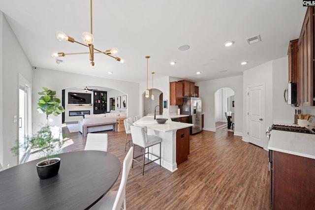 kitchen with arched walkways, ceiling fan with notable chandelier, visible vents, open floor plan, and appliances with stainless steel finishes