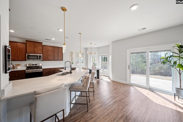 kitchen with visible vents, dark wood-style flooring, stainless steel appliances, a kitchen bar, and a sink