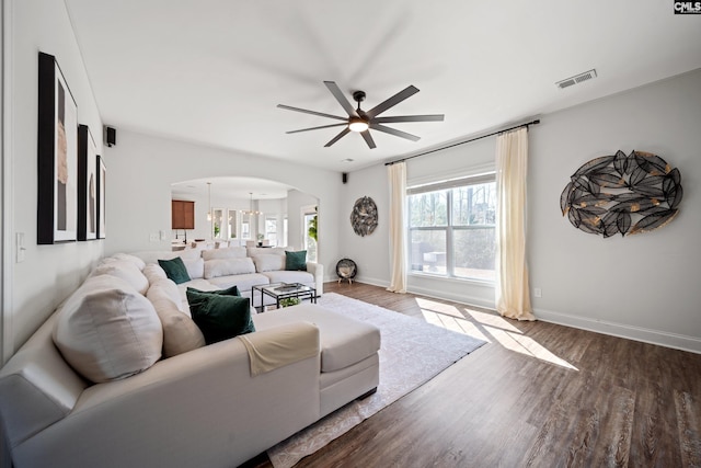 living room featuring arched walkways, wood finished floors, visible vents, and baseboards