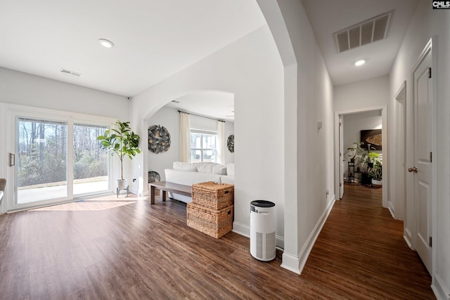 corridor with arched walkways, recessed lighting, visible vents, baseboards, and dark wood finished floors