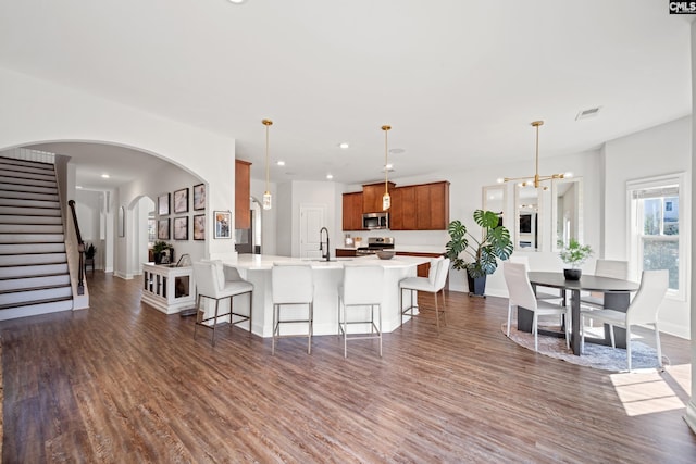 kitchen featuring a breakfast bar, visible vents, appliances with stainless steel finishes, brown cabinets, and dark wood finished floors