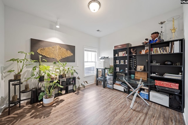 home office with wood finished floors, visible vents, and baseboards