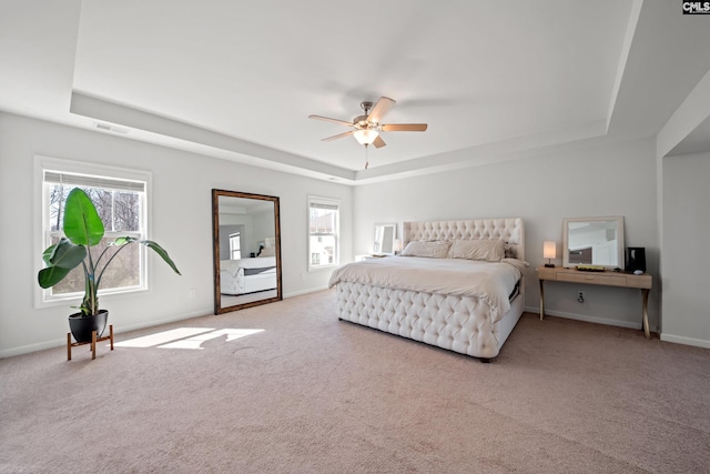 carpeted bedroom with a tray ceiling, visible vents, and baseboards