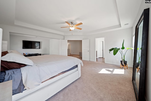 bedroom featuring light carpet, baseboards, visible vents, and a tray ceiling