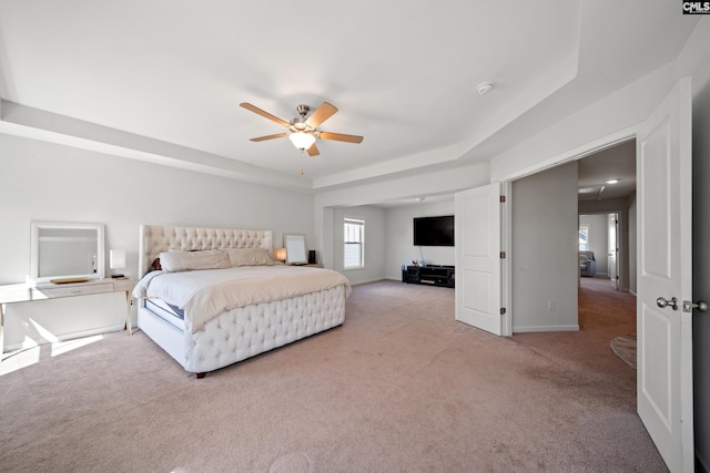 carpeted bedroom featuring ceiling fan, a raised ceiling, and baseboards