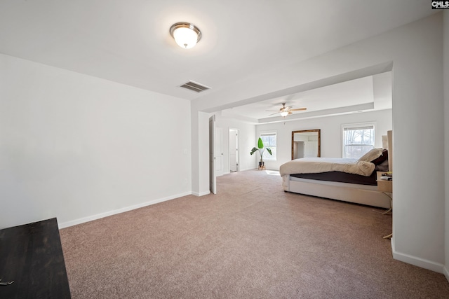 bedroom featuring a tray ceiling, visible vents, a ceiling fan, carpet flooring, and baseboards