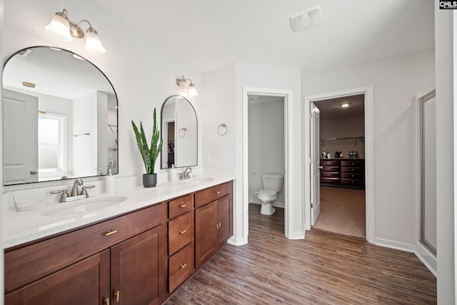 bathroom featuring double vanity, wood finished floors, a sink, and toilet