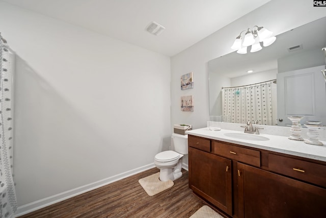 bathroom with baseboards, visible vents, toilet, wood finished floors, and vanity