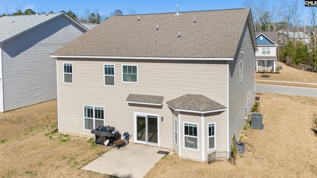 rear view of house with a yard, roof with shingles, a patio, and central AC unit