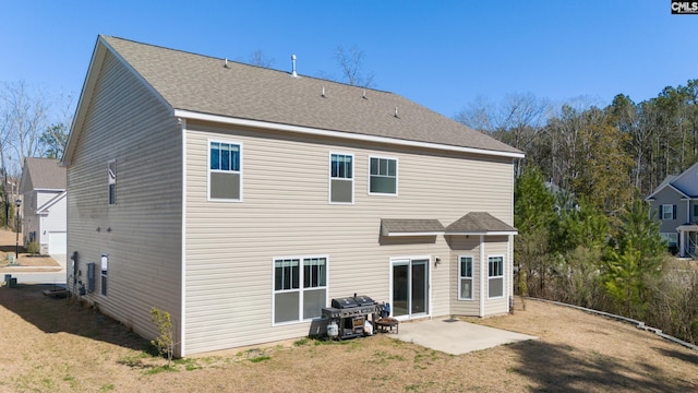 rear view of property with roof with shingles, a patio, and a lawn