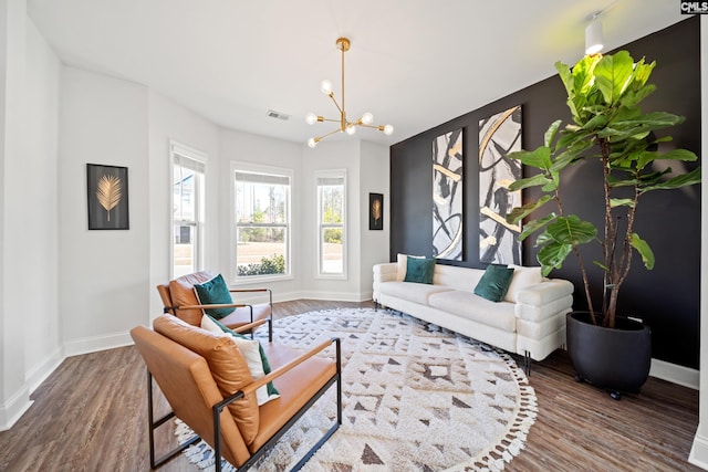 living area with a notable chandelier, visible vents, baseboards, and wood finished floors