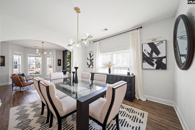 dining room featuring baseboards, visible vents, arched walkways, dark wood-style floors, and an inviting chandelier