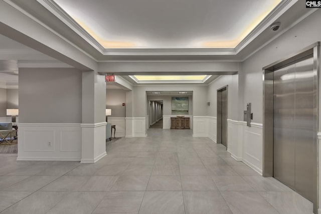 corridor featuring light tile patterned floors, crown molding, a raised ceiling, and elevator