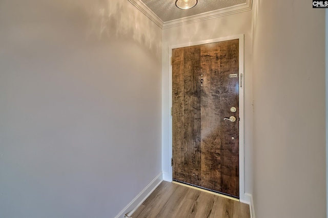 entryway featuring baseboards, crown molding, and wood finished floors