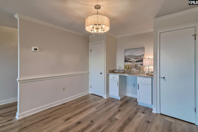 interior space with a textured ceiling, light wood finished floors, an inviting chandelier, and crown molding