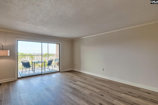 empty room with crown molding, a textured ceiling, baseboards, and wood finished floors