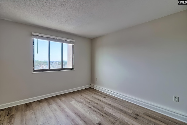 empty room featuring a textured ceiling, baseboards, and wood finished floors