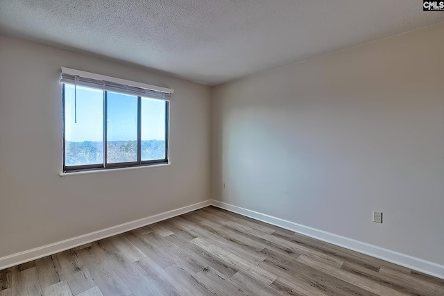 spare room with a textured ceiling, baseboards, and wood finished floors