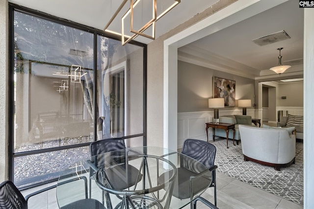 dining space with visible vents, a decorative wall, and wainscoting